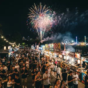 A nighttime festival with fireworks in the sky, food stalls lined up, and crowds mingling. - Google Nano Banana 2 Lite