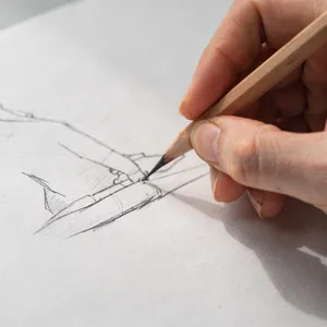 A hand drawing a sketch on paper with a pencil, the hand and pencil tip in clear focus. - Black Forest Labs Flux 2 Pro