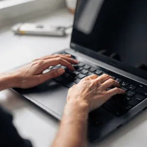 A person typing on a laptop keyboard, showing both hands on the keys. - Black Forest Labs Flux 2 Pro