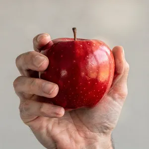 A realistic photo of a hand holding a red apple, with all fingers clearly visible. - Black Forest Labs Flux 2 Pro