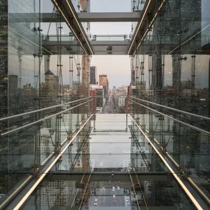 Photorealistic rendering of a contemporary glass skybridge between two skyscrapers, seen from inside with city views visible through glass walls and floor. Show accurate reflections and structural details. - Black Forest Labs Flux 2 Pro