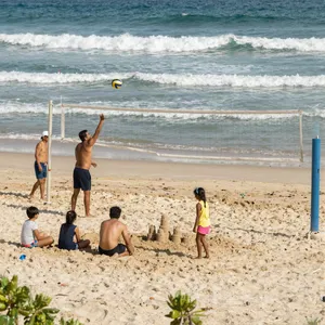 A beach scene: adults playing volleyball, kids building sandcastles, and surfers riding waves. - Alibaba Z-Image Turbo