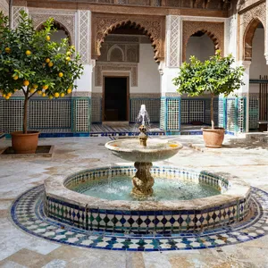 A traditional Moroccan riad courtyard with detailed zellige tilework, flowing fountain, citrus trees, and ornate woodwork. Morning light casting intricate shadow patterns. - Alibaba Z-Image Turbo