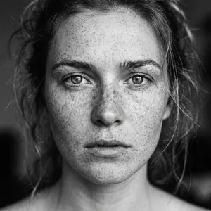A black and white close-up portrait of a freckled woman with an intense gaze. - Google Nano Banana 2.1