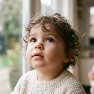 A hyper-realistic photo of a toddler with curly hair and big eyes, looking upward. - Google Nano Banana 2.1