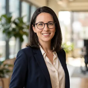 A professional headshot of a businesswoman wearing glasses, against a blurred background. - Google Nano Banana 2.1