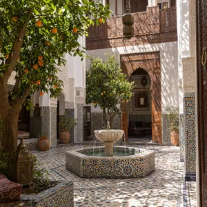 A traditional Moroccan riad courtyard with detailed zellige tilework, flowing fountain, citrus trees, and ornate woodwork. Morning light casting intricate shadow patterns. - OpenAI GPT Image 2.5 Flare