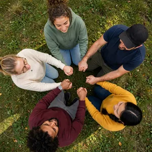 A group of five people joining hands in a circle, seen from above. - Meta Muse Image