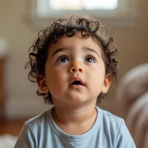 A hyper-realistic photo of a toddler with curly hair and big eyes, looking upward. - XAI Grok Imagine