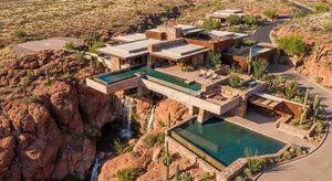 Aerial view of a modernist desert home, in the style of Frank Lloyd Wright's Fallingwater but adapted to desert conditions. Show integration with rocky landscape and water features. - Google Nano Banana Pro