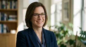 A professional headshot of a businesswoman wearing glasses, against a blurred background. - Google Nano Banana Pro