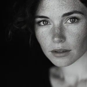 A black and white close-up portrait of a freckled woman with an intense gaze. - Midjourney Midjourney V6.1