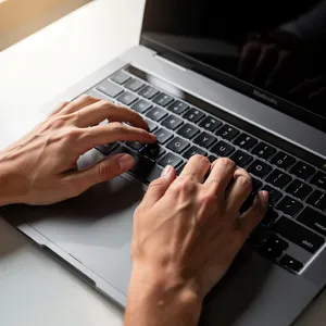 A person typing on a laptop keyboard, showing both hands on the keys. - Black Forest Labs Flux 2 Pro