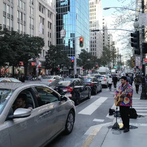 A busy city intersection with cars, pedestrians, and street performers all in one frame. - Black Forest Labs FLUX.1 Kontext Max