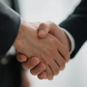 A close-up of two people shaking hands, both hands fully visible with five fingers each, in sharp focus against a blurred background. - Bytedance Seedream 3.0
