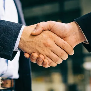 A close-up of two people shaking hands, both hands fully visible with five fingers each, in sharp focus against a blurred background. - Bytedance Seedream 4.5