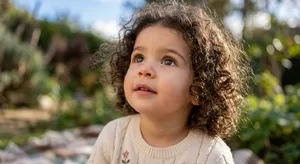 A hyper-realistic photo of a toddler with curly hair and big eyes, looking upward. - Takumi Takumi 1