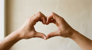 Two hands forming a heart shape together against a plain background. - Takumi Takumi 1