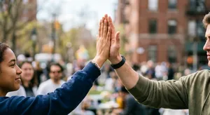 Two people high-fiving, with focus on their hands meeting mid-air. - Takumi Takumi 1