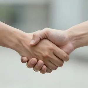 A close-up of two people shaking hands, both hands fully visible with five fingers each, in sharp focus against a blurred background. - Alibaba Z-Image Turbo