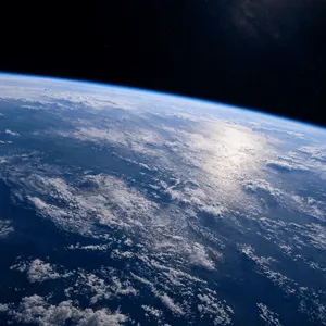 Photorealistic aerial photograph clearly showing the edge of the Earth from space, capturing realistic curvature, atmosphere, and sunlight reflections - Reve Reve 2.1