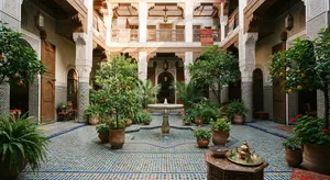 A traditional Moroccan riad courtyard with detailed zellige tilework, flowing fountain, citrus trees, and ornate woodwork. Morning light casting intricate shadow patterns. - Google Nano Banana 2 Lite