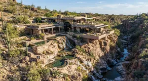 Aerial view of a modernist desert home, in the style of Frank Lloyd Wright's Fallingwater but adapted to desert conditions. Show integration with rocky landscape and water features. - Google Nano Banana 2 Lite