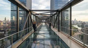 Photorealistic rendering of a contemporary glass skybridge between two skyscrapers, seen from inside with city views visible through glass walls and floor. Show accurate reflections and structural details. - Google Nano Banana 2 Lite