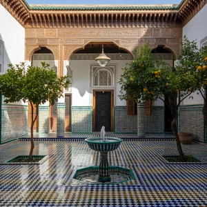 A traditional Moroccan riad courtyard with detailed zellige tilework, flowing fountain, citrus trees, and ornate woodwork. Morning light casting intricate shadow patterns. - Ideogram Ideogram 3.0 (Quality)