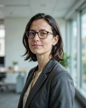 A professional headshot of a businesswoman wearing glasses, against a blurred background. - Ideogram Ideogram 4.0 (Quality)