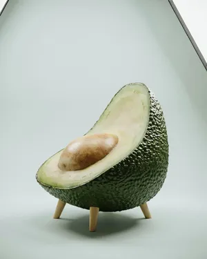 An armchair designed in the shape of an avocado, presented in a contemporary product photography style with professional studio lighting against a minimalist background. - Ideogram Ideogram 4.0 (Quality)
