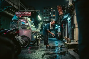 Rain-slicked Singapore street, 3 AM. A lone elderly hawker cleans his cart under one flickering fluorescent light. Steam rises gently. Low-angle shot, photorealistic - Ideogram Ideogram 4.0 (Quality)