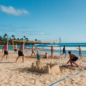 A beach scene: adults playing volleyball, kids building sandcastles, and surfers riding waves. - Ideogram Ideogram V2
