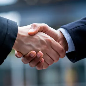 A close-up of two people shaking hands, both hands fully visible with five fingers each, in sharp focus against a blurred background. - Ideogram Ideogram V2