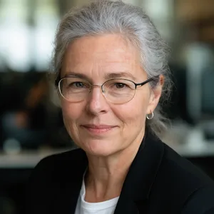 A professional headshot of a businesswoman wearing glasses, against a blurred background. - Krea Krea 2 Large