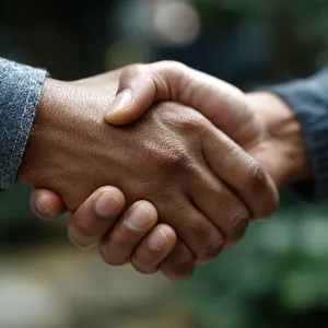 A close-up of two people shaking hands, both hands fully visible with five fingers each, in sharp focus against a blurred background. - Midjourney Midjourney v7
