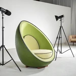 An armchair designed in the shape of an avocado, presented in a contemporary product photography style with professional studio lighting against a minimalist background. - Recraft Recraft V3
