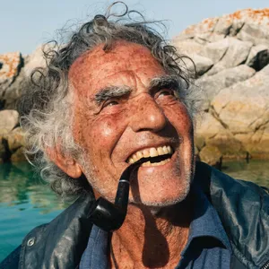 A 4K photo of an old fisherman with a weathered face and a pipe, grinning. - Recraft Recraft V4.1