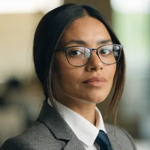 A professional headshot of a businesswoman wearing glasses, against a blurred background. - Recraft Recraft V4.1