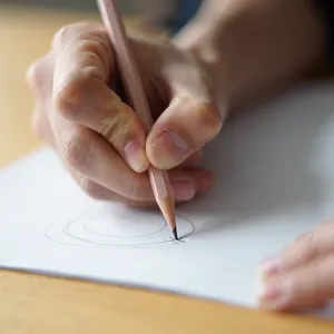 A hand drawing a sketch on paper with a pencil, the hand and pencil tip in clear focus. - Reve Reve Image (Halfmoon)