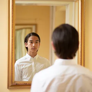 A person standing before a mirror, with their front and reflected back both visible. - Reve Reve Image (Halfmoon)