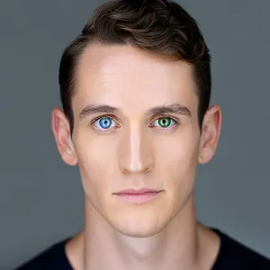 A studio headshot of a young man with one blue eye and one green eye (heterochromia). - Reve Reve Image (Halfmoon)