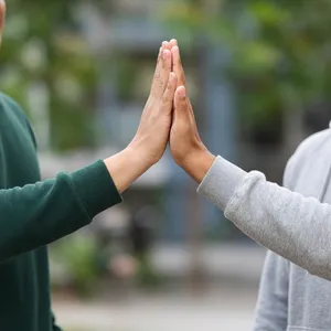 Two people high-fiving, with focus on their hands meeting mid-air. - XAI Grok Imagine 2.0