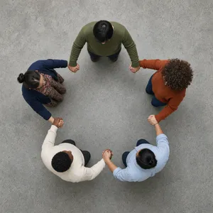A group of five people joining hands in a circle, seen from above. - XAI Grok Imagine 2.0 (Preview)