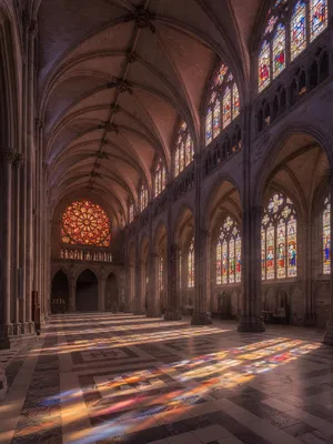 A Gothic cathedral interior at sunset with light streaming through detailed stained glass windows, creating colored patterns on stone floors and columns. Show accurate ribbed vaulting. - XAI Grok Imagine (Quality)