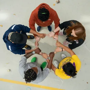A group of five people joining hands in a circle, seen from above. - XAI Grok Imagine (Quality)
