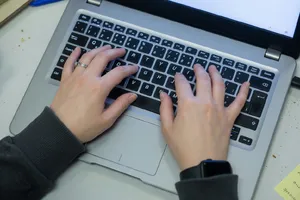 A person typing on a laptop keyboard, showing both hands on the keys. - XAI Grok Imagine (Quality)