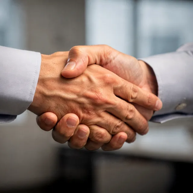 A close-up of two people shaking hands, both hands fully visible with five fingers each, in sharp focus against a blurred background. - Flux 2 Pro