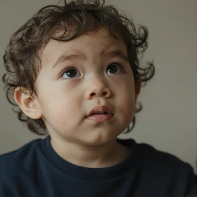 A hyper-realistic photo of a toddler with curly hair and big eyes, looking upward. - Z-Image Turbo