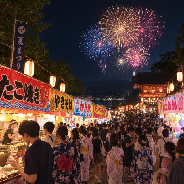 A nighttime festival with fireworks in the sky, food stalls lined up, and crowds mingling. - GPT Image 2.5 Flare